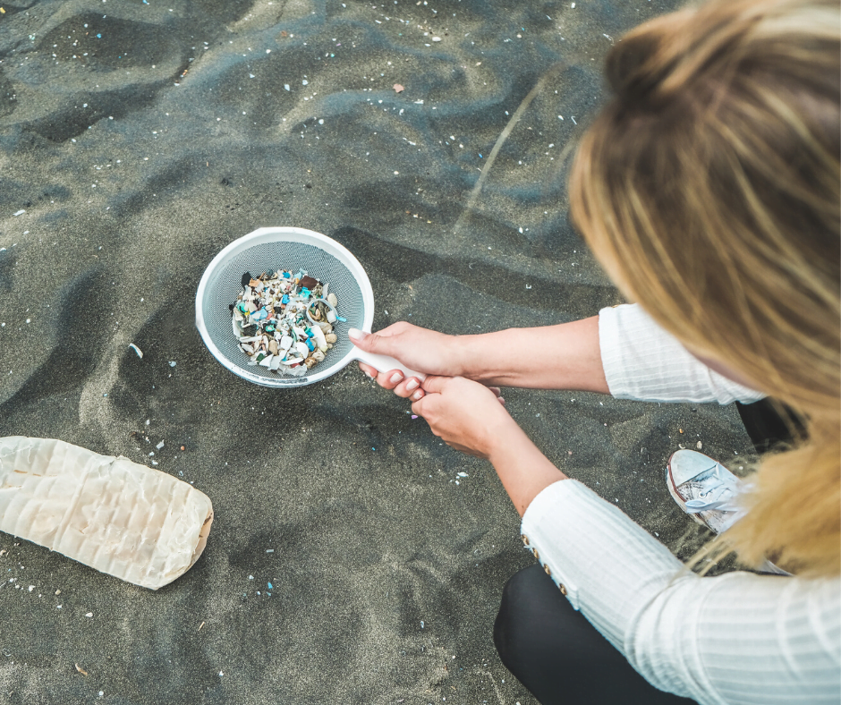 Femme ramassant des morceaux de microplastiques mélangé au sable d'une plage